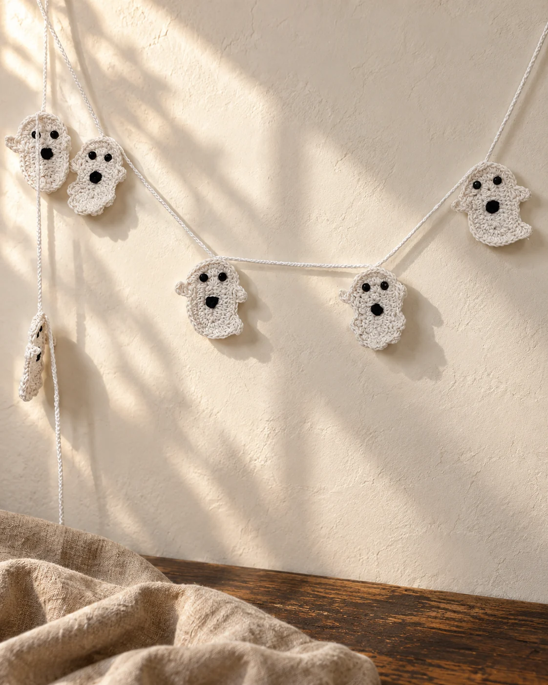 White crochet ghost figures arranged along a Halloween garland.