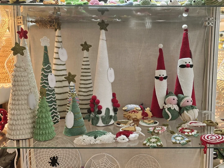Crocheted Christmas trees, Santa figures and festive decorations on a glass shelf at our stall, IHGF Delhi Fair Autumn 2025.