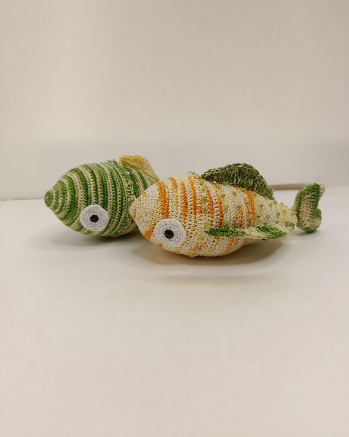 Pair of green, cream and orange crocheted fish.